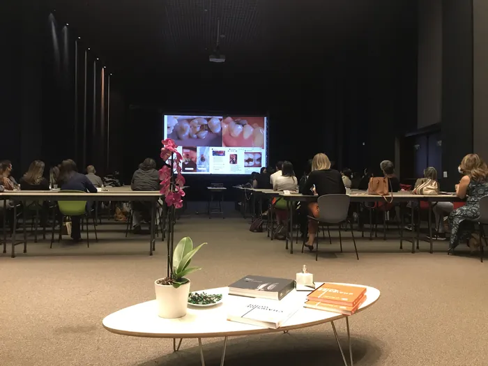 Auditório com mesa de centro decorada com orquídea e livros