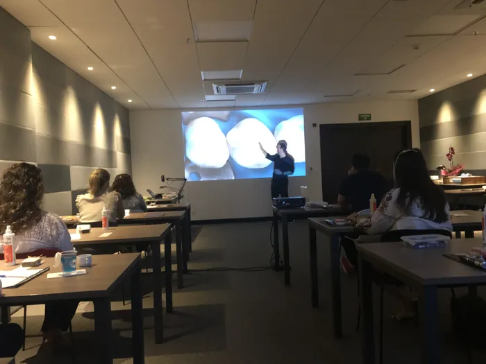 Sala de aula com bancadas e demonstração no telão