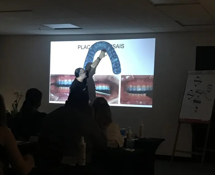 Professor mostrando uma placa oclusal à turma